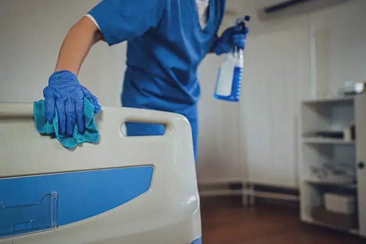 Female nurse cleaning the bed after patients in hospital ward.
